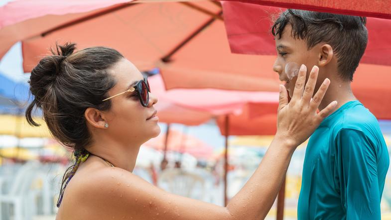 Una mama aplicando filtro solar a la cara de su hijo