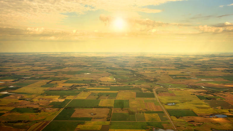 Aerial image of brown and green rural land against a yellow sunrise
