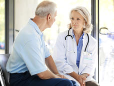 Older male patient sitting and talking with female doctor