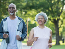 An older African American couple walking in a park.