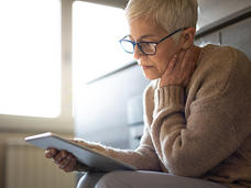 An older woman reading a tablet.