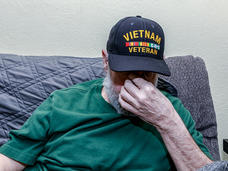 A depressed Vietnam War USA military veteran has his head down while covering his face with his hand