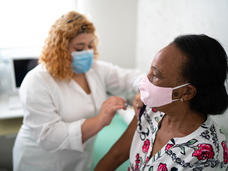 Una enfermera vacunando a una mujer negra mayor.
