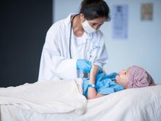 A female doctor talks with a child laying in a hospital bed.