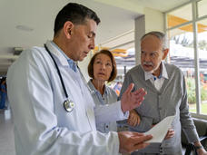 Un hombre y una mujer mayores escuchan con atención a un médico.