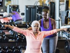 Older African-American woman lifting weights in a gym