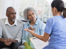 Female health professional explaining medical information to middle-aged couple. 
