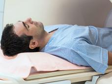 A young white male laying flat, entering an MRI machine.