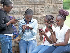 Cuatro adolescentes kenianas mirando su teléfono celular