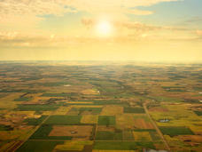 Aerial image of brown and green rural land against a yellow sunrise