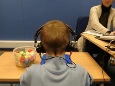 child in earphones sitting at a table