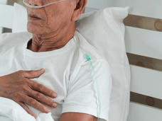 A photo of an older man in a hospital bed with a canula in his nose.