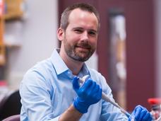 Photo of Dr. Kevin Janes in his laboratory holding a pipet