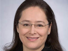 A professional headshot of Dr. Paula Aristizabal, a Latina with a light skin tone, dark hair, and glasses, smiling at the camera.