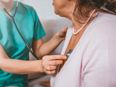 A health provider holding a stethoscope to a woman's chest.