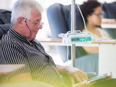 An older man in a recliner receiving outpatient IV cancer medication