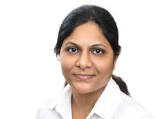 Headshot of Indian woman (Dr. Subhashini Jagu) with hair tied back in a ponytail, wearing a white shirt in front of a white background.