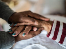 A pair of hands clasping the hands of another person.