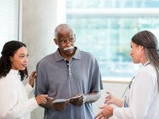 man with white mustache and his daughter talk to a doctor