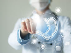Photo of a doctor pointing to a virtual visualization model of the stomach. Also shown are several medical-related icons.