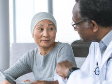 Photo of a woman in head covering sitting and meeting with her doctor.