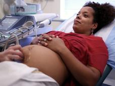 pregnant person lies on an exam table while receiving an ultrasound