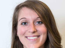 A woman, Dr. Mary Frances Wedekind, with brown hair, brown eyes, and freckles stands smiling at the camera.