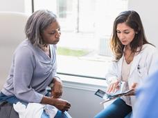 A young female doctor talking with an older female patient