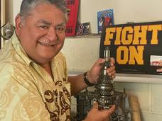 A picture of Adan Reinosa in his garage with a piece of a car engine.