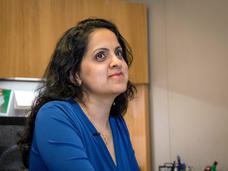 Woman with short brown hair and blue blouse (Payal Khincha) sitting in her office.