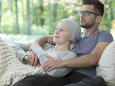 Sick woman lying in man's arms relaxing on couch.