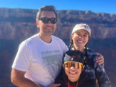 Woman, Dr. Fernanda Michels, with two long braids wearing a ballcap and sweater with her husband and young son at the Grand Canyon.