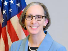 NCI Director Dr. Rathmell stands in front of the U.S. flag