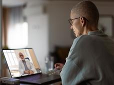 Middle-aged woman with cancer having a virtual appointment with doctor on the computer.