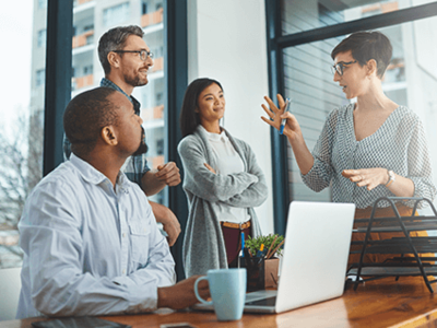Three people listen attentively to their colleague explaining a concept