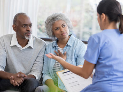 Female health professional explaining medical information to middle-aged couple. 