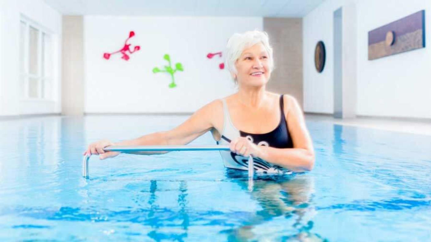 Woman with white hair doing water aerobics.
