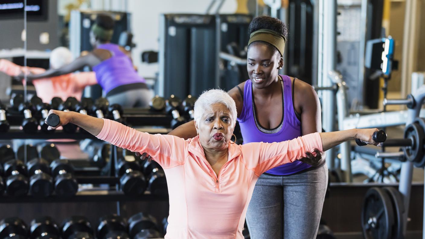 Older African-American woman lifting weights in a gym