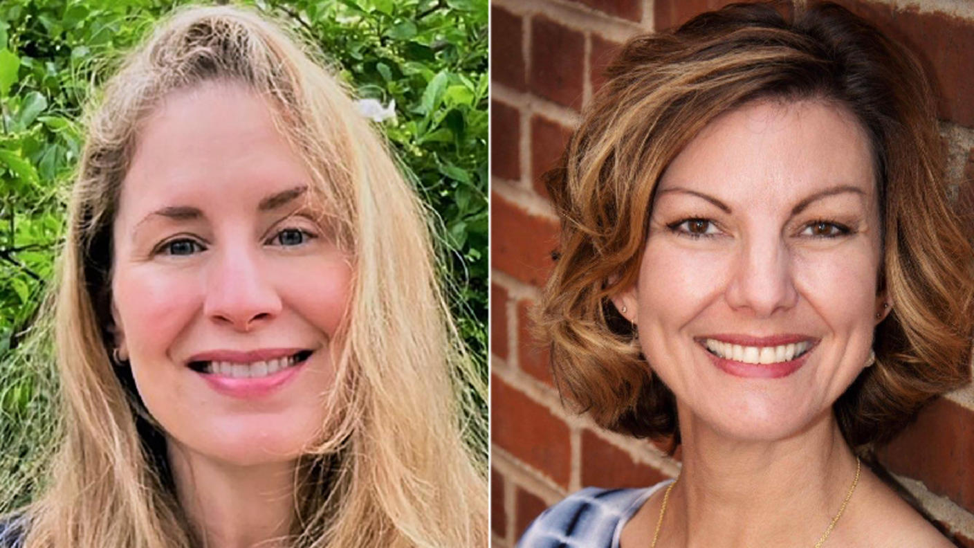 Two women smiling at the camera. One has blonde hair and is wearing a white top. The other has brown hair and is wearing a blue and white top.