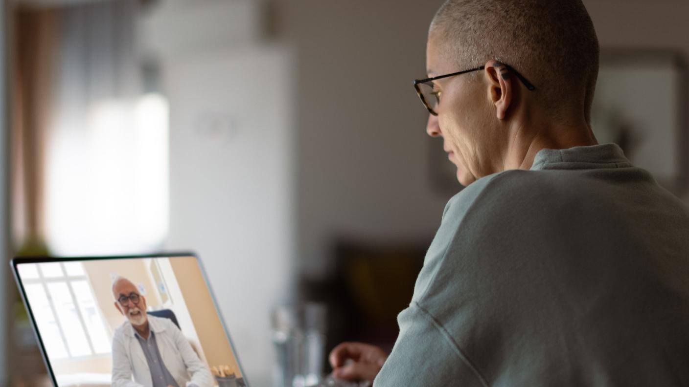 Middle-aged woman with cancer having a virtual appointment with doctor on the computer.