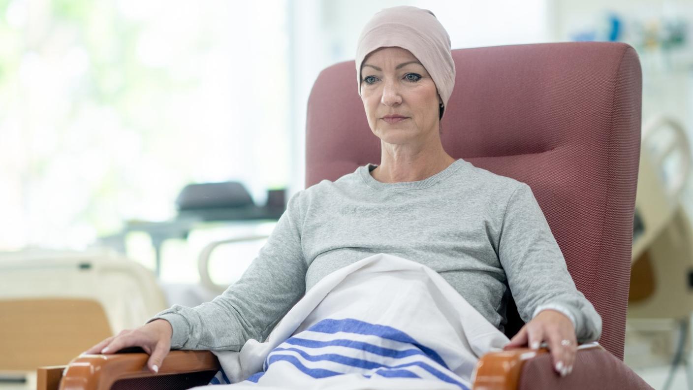 A middle-aged woman in a reclining chair receiving chemotherapy