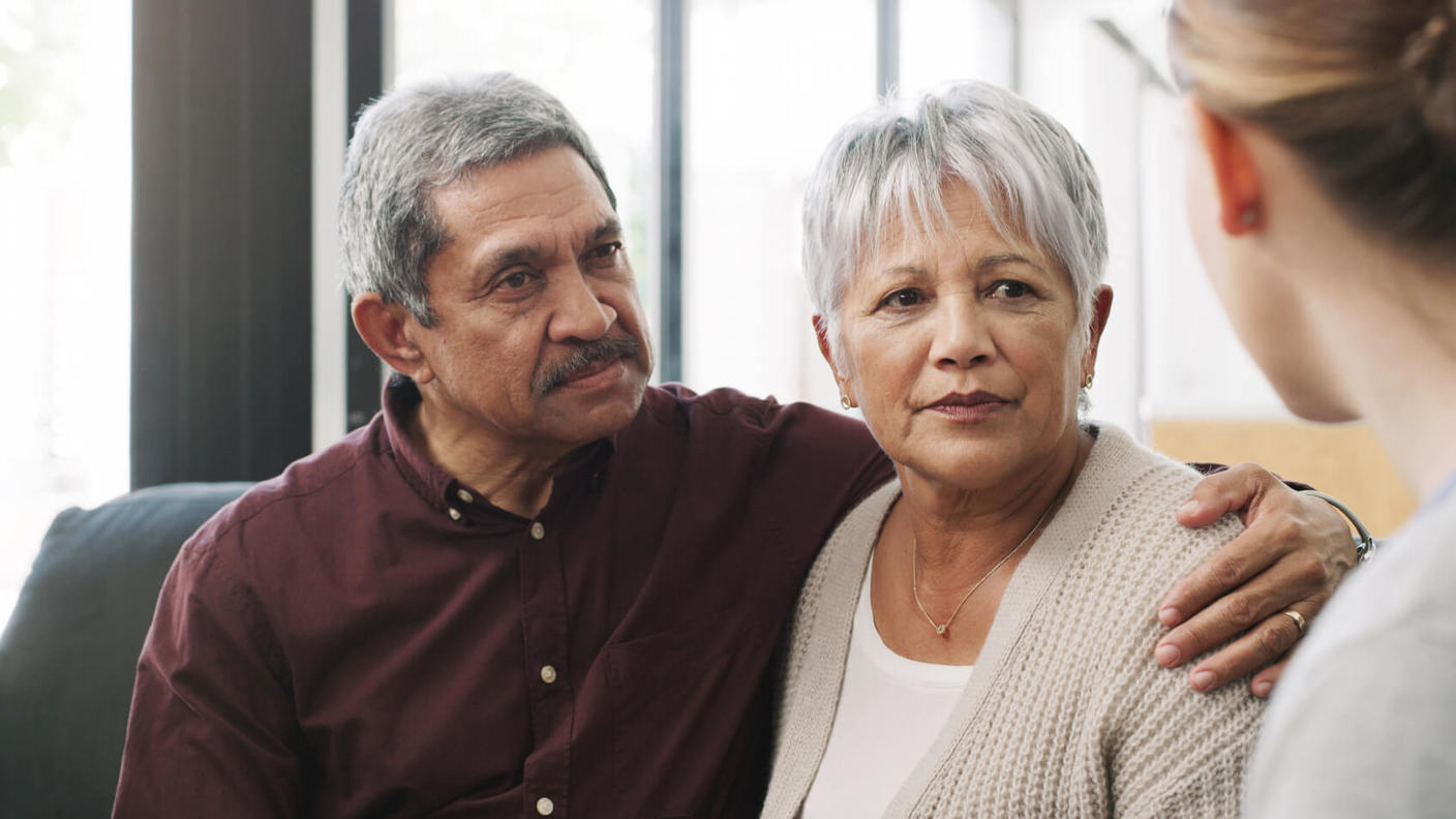 Una pareja de adultos mayores escucha con atención mientras el médico habla.