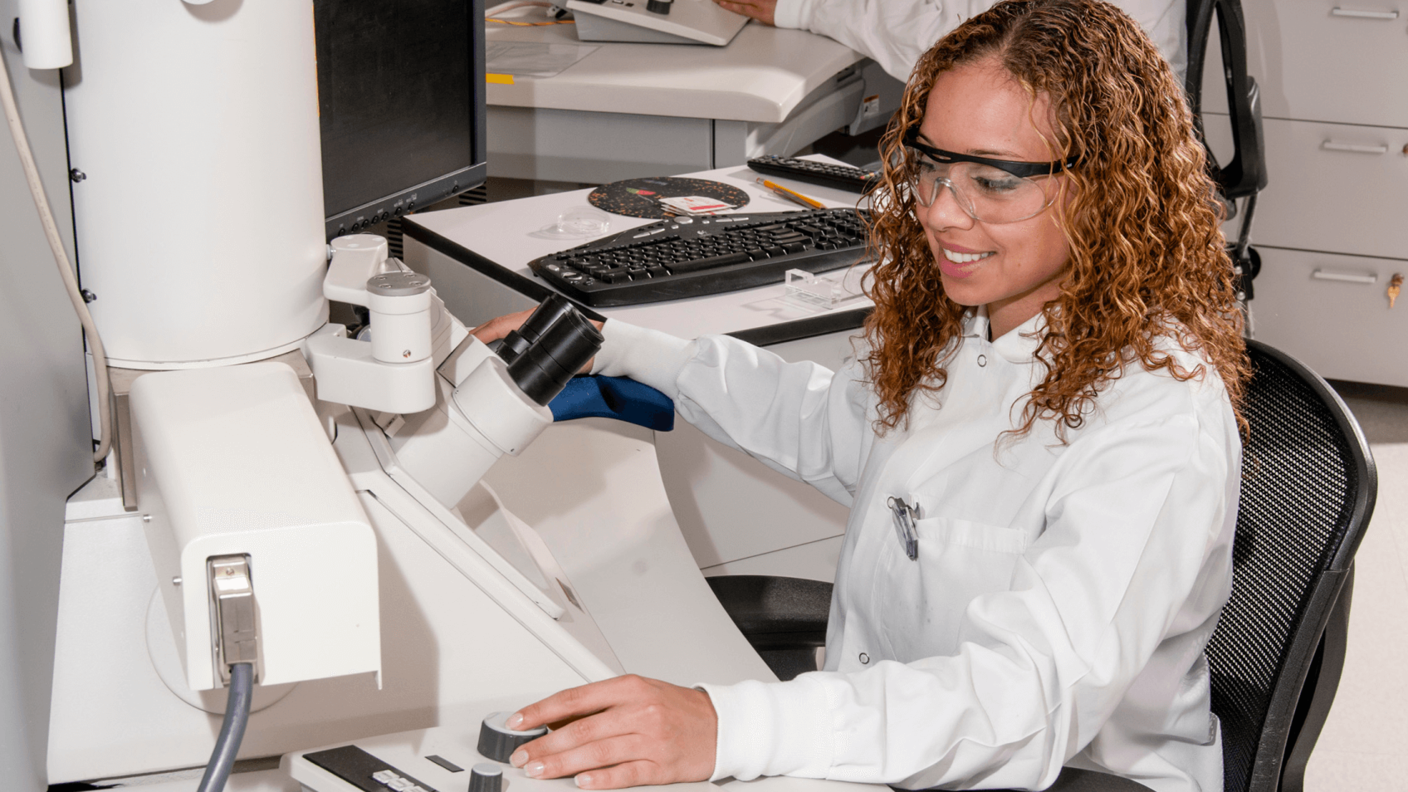 Una auxiliar de laboratorio utilizando un microscopio electrónico.