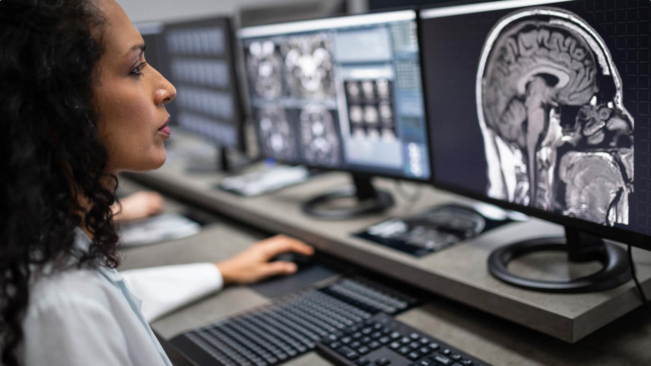 Female health care worker looking at an MRI image on a computer.
