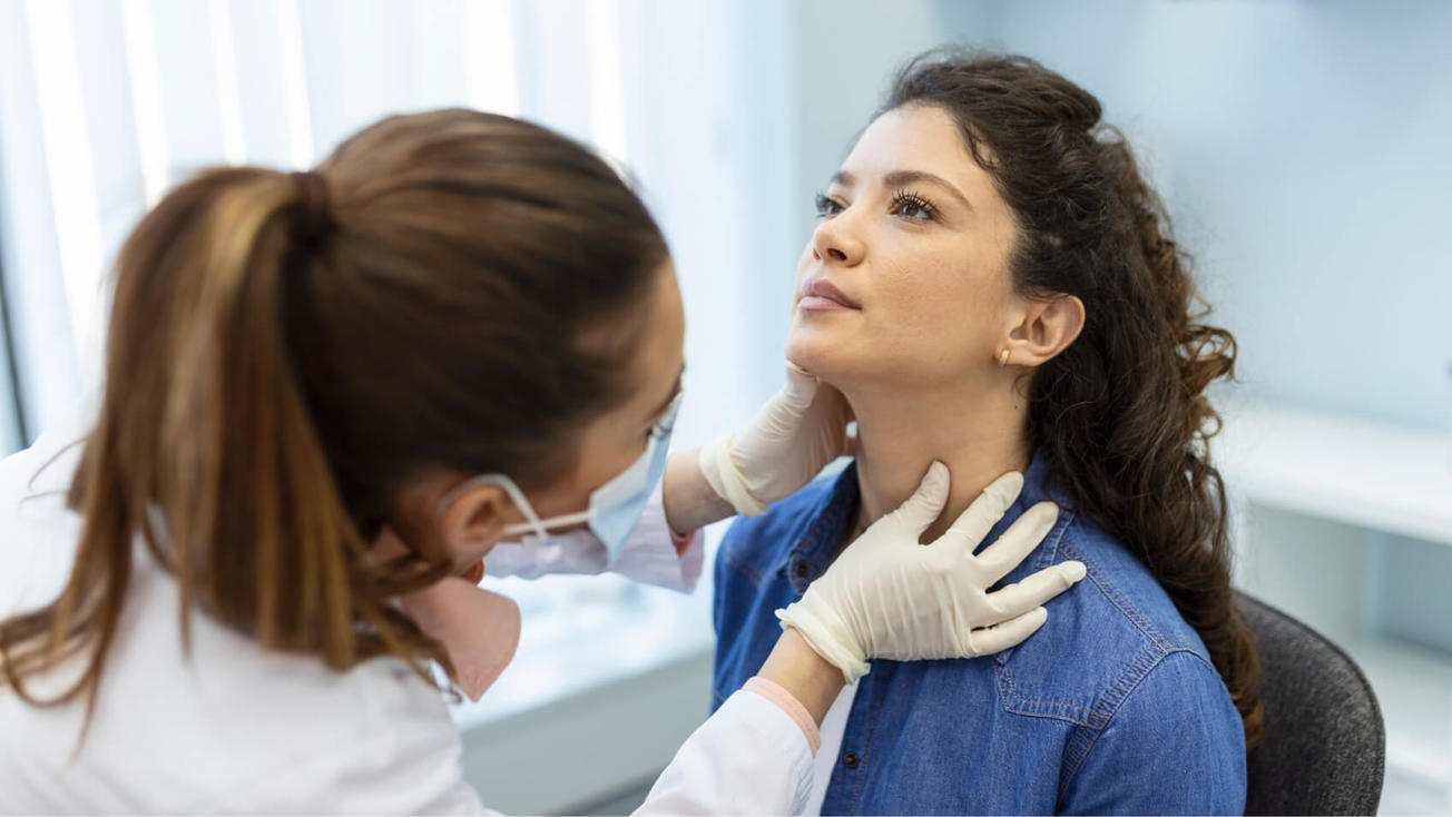 Una médica le examina la cabeza y el cuello a una mujer 