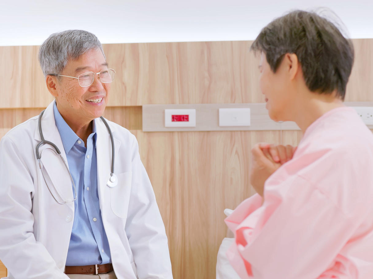 Senior male doctor talking with older female patient.