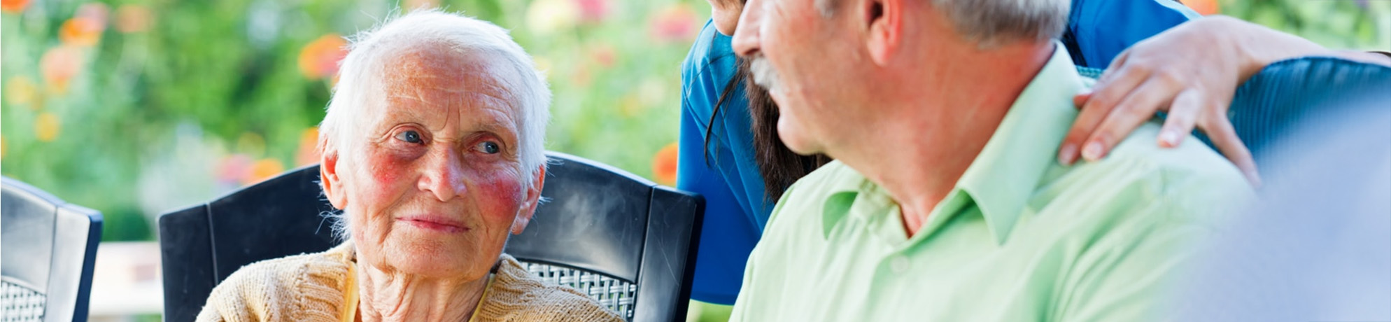 Elderly woman and man looking at each other outside with nurse.