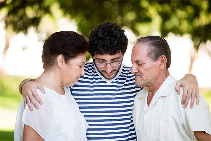 Grandson praying with grandparents