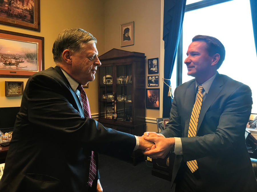 Dr. Norman E. Sharpless shakes hands with Representative Tom Cole in an office.
