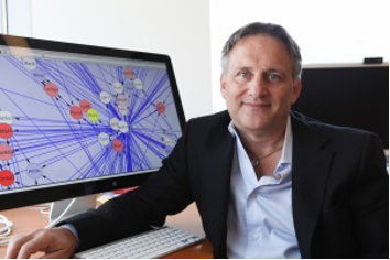 Andrea Califano sits in a chair next to a computer monitor.